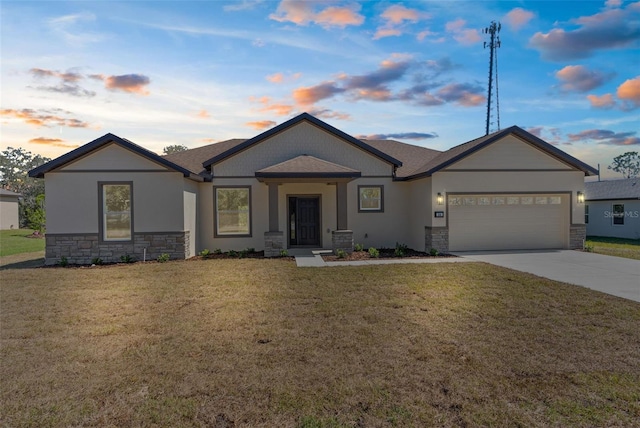 view of front of property with a yard, stone siding, concrete driveway, and a garage