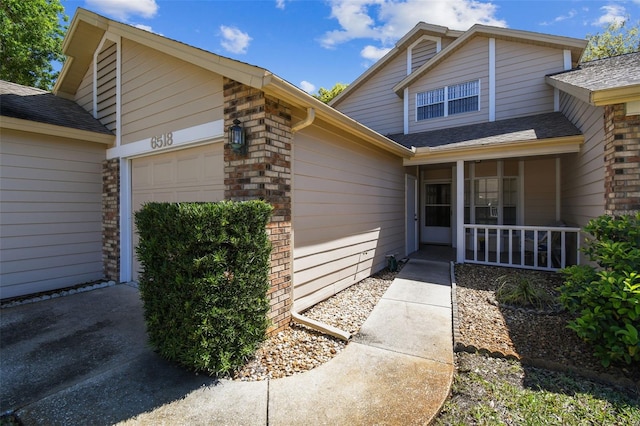 view of front of property featuring a porch, an attached garage, and brick siding