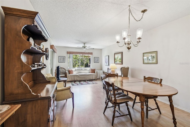 dining room featuring baseboards, ceiling fan with notable chandelier, a textured ceiling, and light wood-style floors