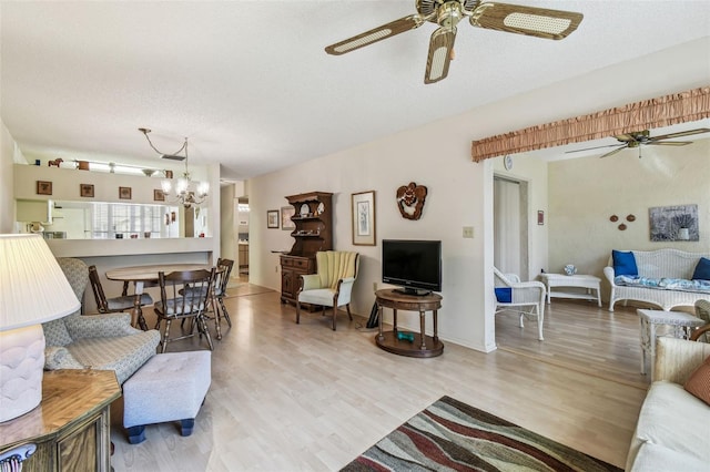 living room with wood finished floors, ceiling fan with notable chandelier, and a textured ceiling