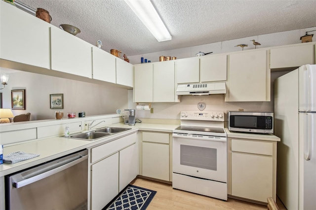 kitchen with a sink, light countertops, appliances with stainless steel finishes, a textured ceiling, and under cabinet range hood