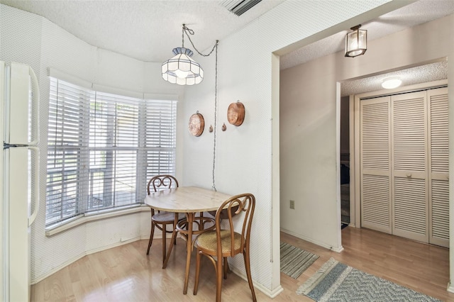 dining area with visible vents, baseboards, a textured ceiling, and wood finished floors