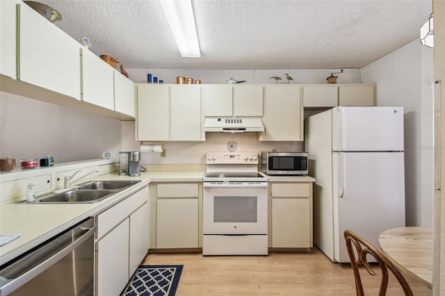 kitchen featuring a sink, stainless steel appliances, light countertops, light wood-style floors, and under cabinet range hood