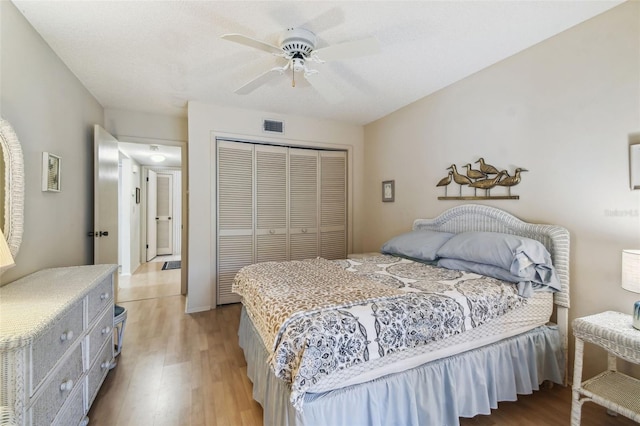 bedroom with light wood-style flooring, a ceiling fan, visible vents, and a closet