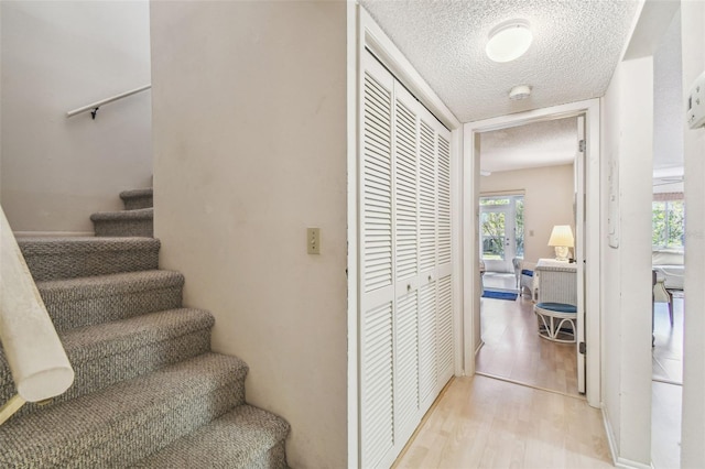 staircase with wood finished floors and a textured ceiling