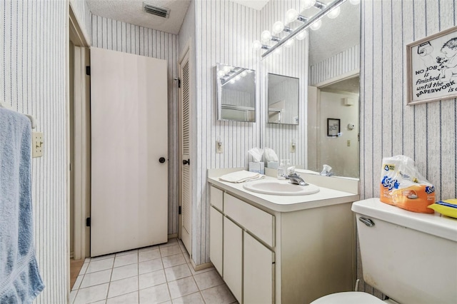 bathroom featuring tile patterned floors, visible vents, a textured ceiling, and wallpapered walls