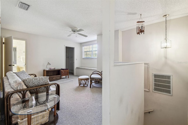 living area with visible vents, a textured ceiling, and ceiling fan