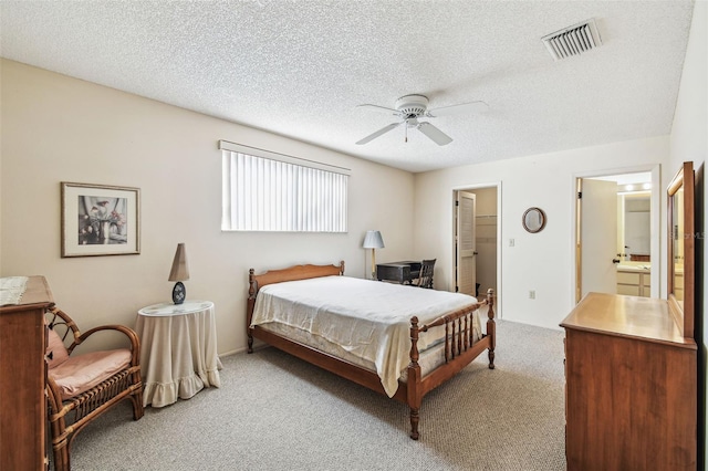 bedroom featuring a textured ceiling, a ceiling fan, visible vents, and light carpet