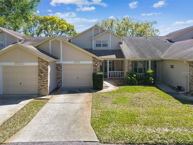 view of front of home with brick siding, a front lawn, roof with shingles, a garage, and driveway