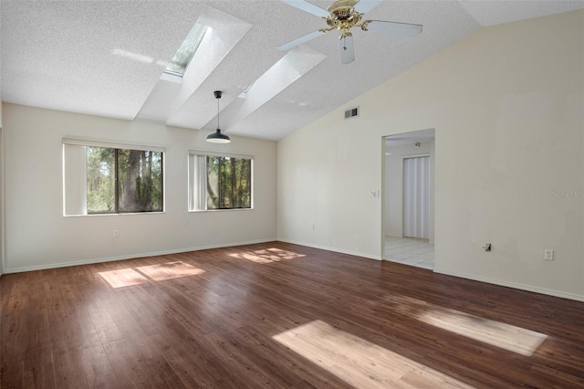 spare room featuring visible vents, a textured ceiling, a skylight, light wood finished floors, and baseboards