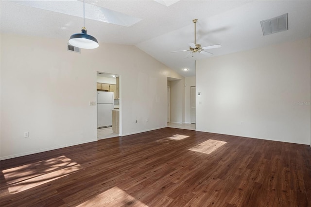 empty room with visible vents, vaulted ceiling with skylight, ceiling fan, and wood finished floors