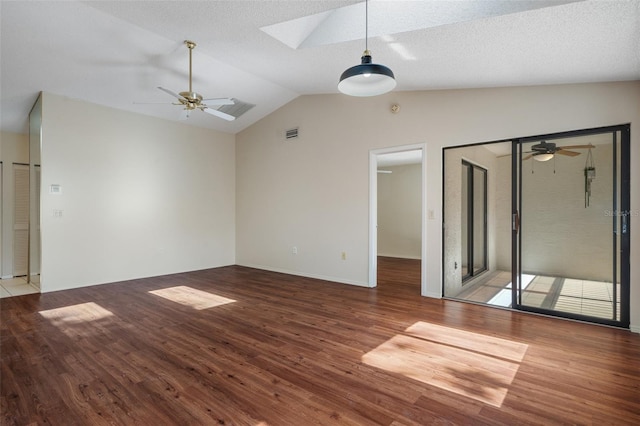 interior space featuring lofted ceiling with skylight, visible vents, a ceiling fan, and wood finished floors