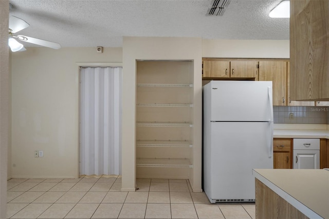 kitchen featuring light tile patterned floors, visible vents, freestanding refrigerator, ceiling fan, and light countertops