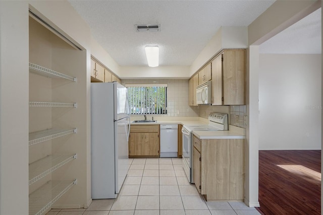 kitchen with visible vents, backsplash, white appliances, light tile patterned flooring, and light countertops