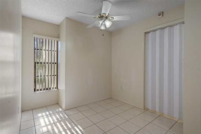 unfurnished room with light tile patterned flooring, a healthy amount of sunlight, a textured ceiling, and a ceiling fan