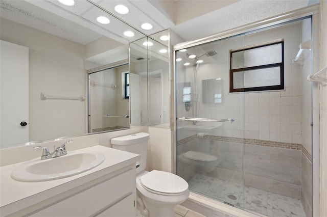 bathroom featuring a stall shower, toilet, and vanity