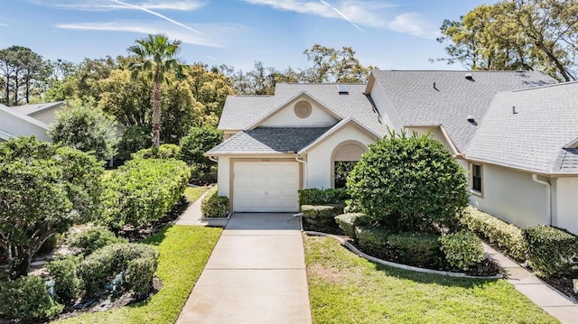 view of front of house featuring a front yard, driveway, roof with shingles, an attached garage, and stucco siding