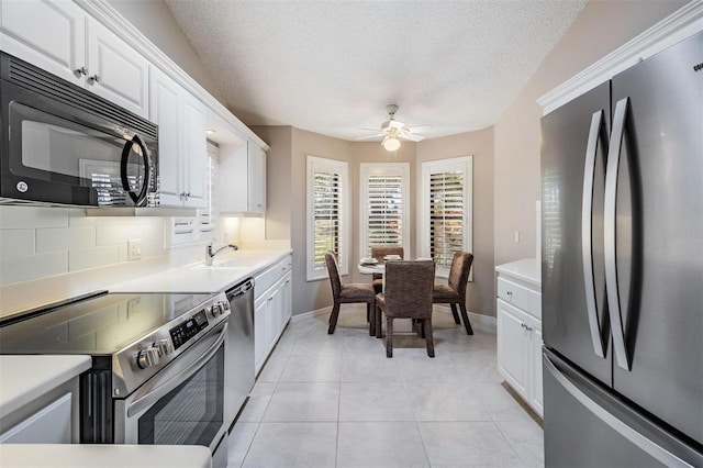 kitchen featuring a sink, ceiling fan, stainless steel appliances, white cabinets, and backsplash