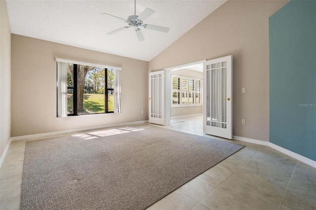 carpeted empty room featuring baseboards, french doors, tile patterned floors, high vaulted ceiling, and a ceiling fan