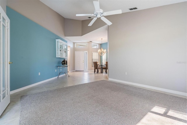 empty room with light tile patterned flooring, visible vents, high vaulted ceiling, and baseboards