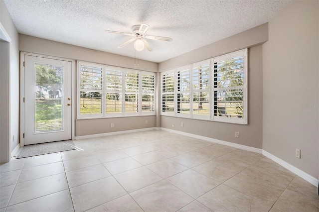 empty room featuring baseboards, a textured ceiling, light tile patterned flooring, and a ceiling fan