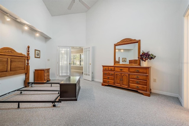 carpeted bedroom with track lighting, baseboards, and a towering ceiling