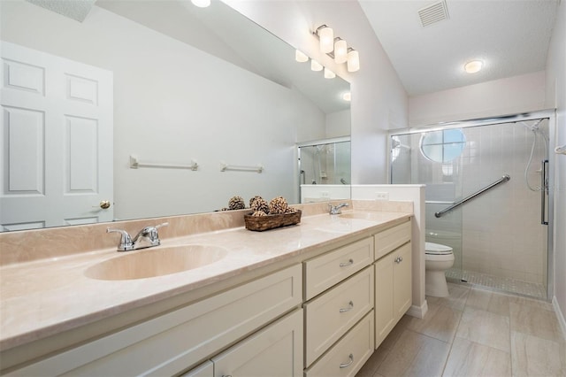 full bath with visible vents, toilet, a stall shower, a sink, and double vanity