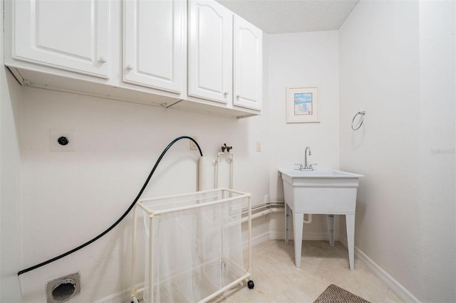 clothes washing area featuring baseboards, cabinet space, and hookup for an electric dryer