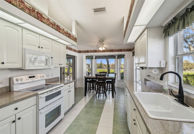 kitchen featuring a sink, visible vents, white appliances, and decorative backsplash