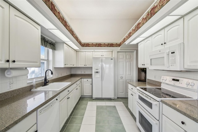 kitchen featuring light tile patterned floors, decorative backsplash, white cabinets, white appliances, and a sink