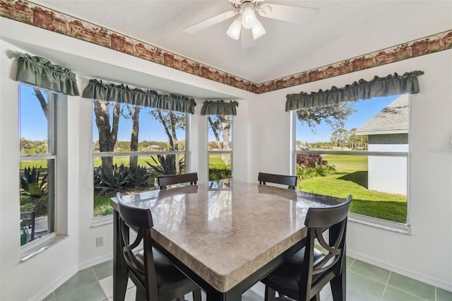 tiled dining room with vaulted ceiling, baseboards, and ceiling fan