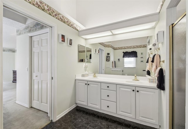 full bath featuring a sink, baseboards, a stall shower, and double vanity