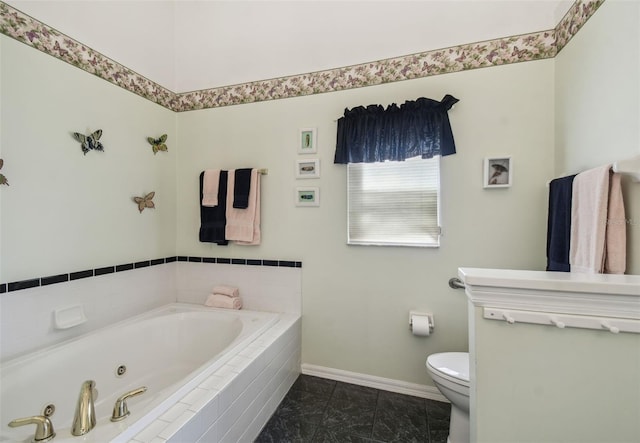 bathroom with baseboards, toilet, and a tub with jets