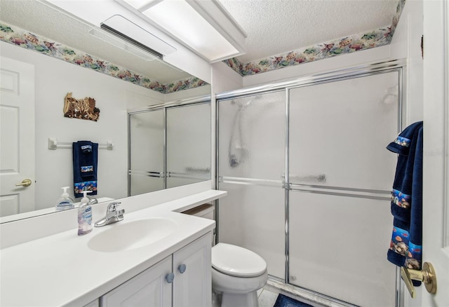 bathroom featuring a textured ceiling, a stall shower, vanity, and toilet