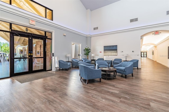 living area with wood finished floors, visible vents, and arched walkways