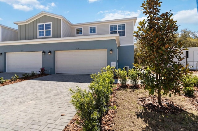 view of front facade with stucco siding, board and batten siding, and decorative driveway