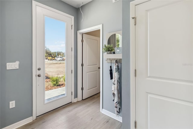 doorway to outside with baseboards, plenty of natural light, and light wood finished floors