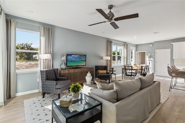 living room with light wood-style flooring, plenty of natural light, and ceiling fan