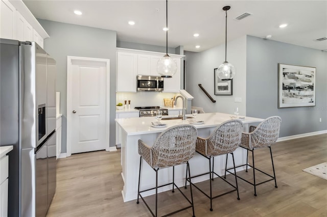 kitchen with visible vents, light wood-type flooring, a kitchen breakfast bar, stainless steel appliances, and a sink