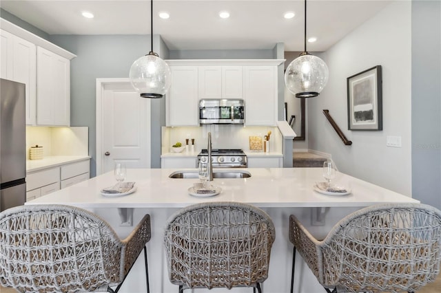 kitchen featuring white cabinetry, a kitchen breakfast bar, stainless steel appliances, and an island with sink