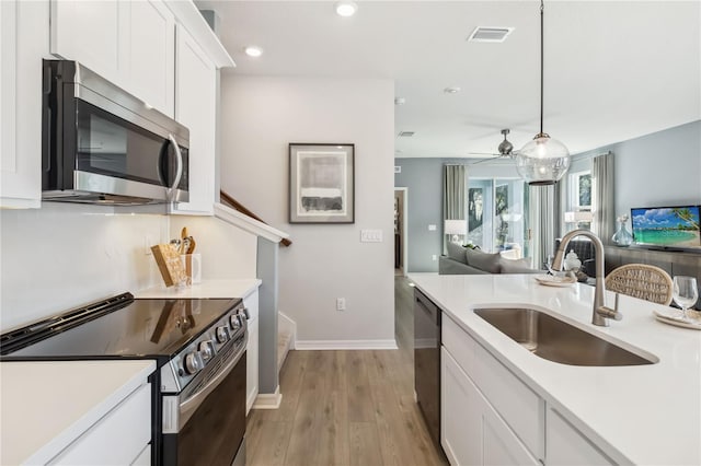 kitchen featuring visible vents, a sink, stainless steel appliances, white cabinetry, and open floor plan