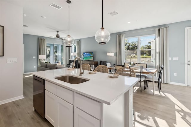 kitchen featuring visible vents, a sink, open floor plan, light countertops, and dishwasher