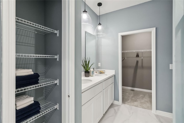 full bath with a spacious closet, baseboards, double vanity, marble finish floor, and a sink