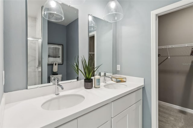 bathroom with a spacious closet, double vanity, baseboards, and a sink