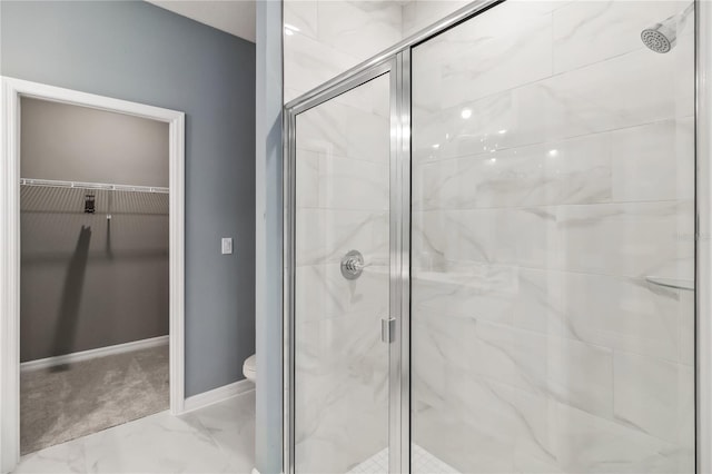 bathroom with a spacious closet, marble finish floor, a stall shower, and toilet