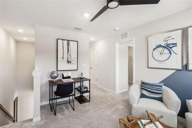 office space featuring baseboards, a ceiling fan, visible vents, and light carpet