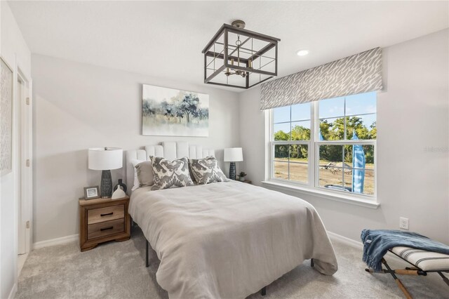 bedroom with a notable chandelier, baseboards, and light carpet