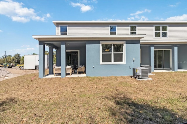 back of house featuring a patio, a lawn, central AC, and stucco siding