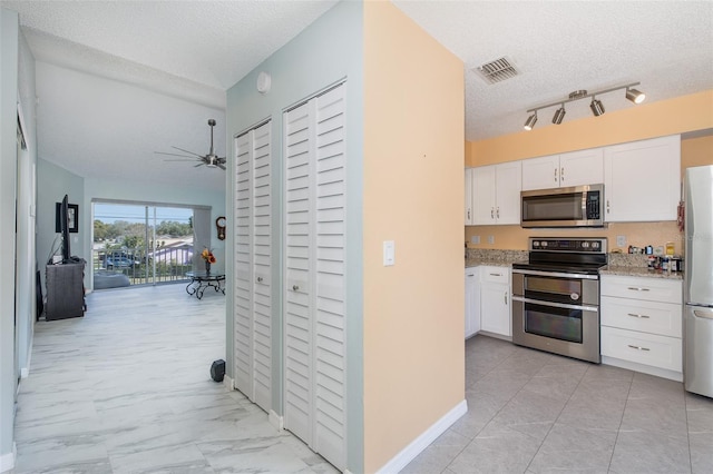 kitchen with visible vents, white cabinets, stainless steel appliances, marble finish floor, and a ceiling fan