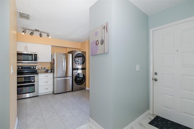 kitchen featuring stacked washer / dryer, visible vents, stainless steel appliances, marble finish floor, and a textured ceiling